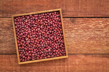 Japanese adzuki (aduki, azuki) beans in a wooden box against rustic barn wood with a copy space