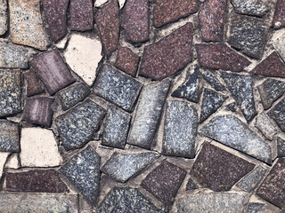 The pattern of granite, stone, bricks, and cement. The texture of the wall of stone. Gray, white and brown colors, convex stones. Old wall background for the site, presentation, or any other creative