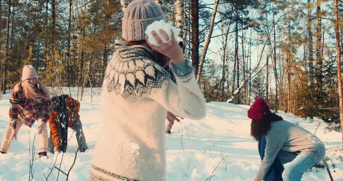 Idyllic cinematic shot, happy friends enjoying snowball fight at magnificent snowy winter forest with dog slow motion.