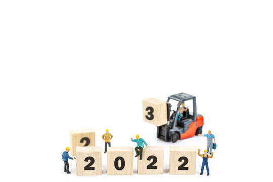 miniature worker team building standing front of forklift machine with   2022 number on wooden block on white background decoration to Happy new year 2022 concept.