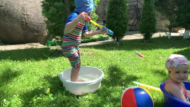 Cute Happy Kid Little Child Preschool Baby Boy in Panama Play Have Fun with Water Pump Gun Outside. Sunny Hot Nice Day in Park. Children Backyard Garden Game. Summer, Sport, Holiday, Family, Childhood