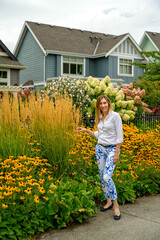 Happy and satisfied middle aged woman taking care of her ornamental plants in a small Canadian garden city