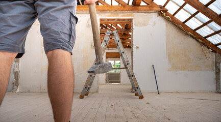 Construction worker with a hammer during the renovation of the attic of a house.