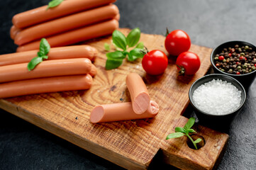 Classic pork sausages on a cutting board with basil and ketchup on a stone background