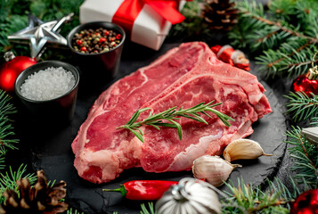 Christmas raw T-bone steak with Christmas tree decorations on stone background