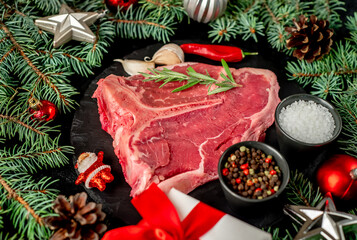 Christmas raw T-bone steak with Christmas tree decorations on stone background