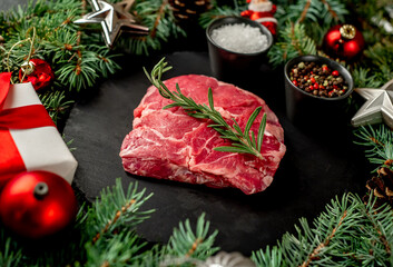 Christmas raw ribeye steak with Christmas tree decorations on stone background