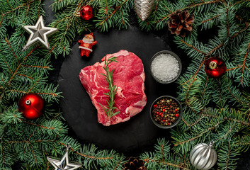 Christmas raw ribeye steak with Christmas tree decorations on stone background