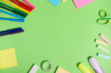Flat lay composition with stationery office or school supplies scattered in a circle on a light green background with copy space. Teacher's day concept