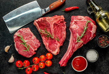A variety of raw steaks. Ribeye steak, tomahawk, T-bone, on a stone background