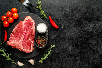 raw T-bone steak with spices ingredients on a stone background with copy space for your text
