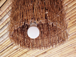 Decorative lamp with bamboo lampshade against the background of a bamboo ceiling