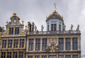 Fototapeta na wymiar Brussels, Belgium - July 31, 2021: Grand Place or Grote Markt. Facade tops of La Brouette and Le Roy D'Espagne guild houses against gray sky. Statues and golden ornaments.