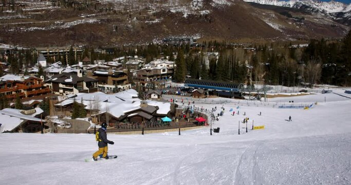 Panning Shot Of People Snowboarding Over Snowy Landscape On Sunny Day During Getaway Vacation - Vail, Colorado