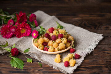 Autumn still life. Raspberries and asters. Vegan food. Red and yellow raspberries on a plate. Berry harvest