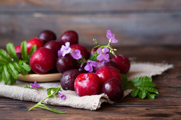 Autumn still life. Plums and flowers. Vegan food on a wooden background. Raw food. Fruit harvest.