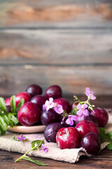 Autumn still life. Plums and flowers. Vegan food on a wooden background. Raw food. Fruit harvest.