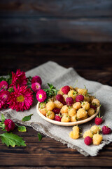 Autumn still life. Raspberries and asters. Vegan food. Red and yellow raspberries on a plate. Berry harvest