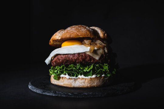 Delicious burger with egg on slate board