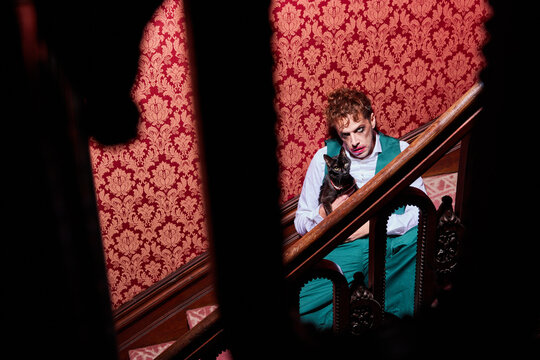 Angry male actor sitting with cat on stairs