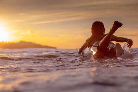 Sunset scene with a girl on a surfboard