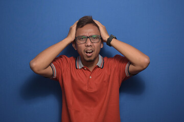 Fototapeta na wymiar Asian man wearing orange casual tshirt with hand on head headache because stress suffering migraine