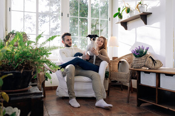 Couple embracing Fox Terrier in armchair at home