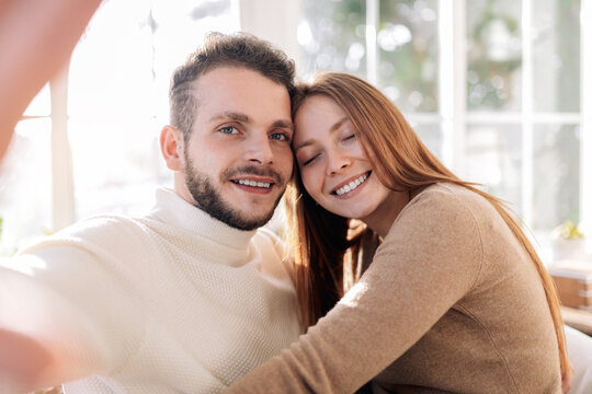Smiling couple taking selfie in house room