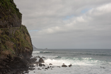 Fototapeta na wymiar Waves crashing on the rocks. Atlantic Ocean shore in Sao Vicente, north of Madeira Island. High cliff. Selective focus. 