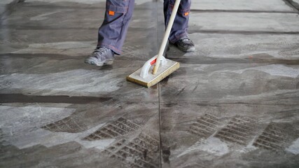 The tiler washes the tiles after work. A worker cleans the tiles on the floor after gluing.