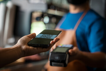 Paying with Mobile Phone,Mobile payment,customer pays a bill payment via a smartphone using NFC technology in a cafe.