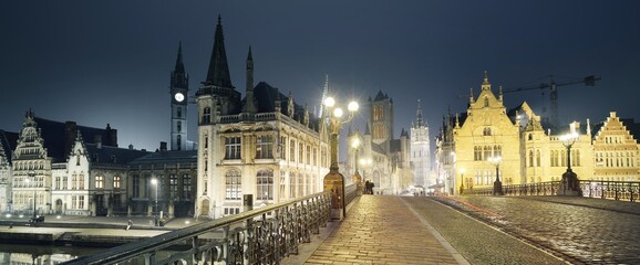 Illuminated street near St Michael bridge and St Bavo's Cathedral in a historical center of Ghent...