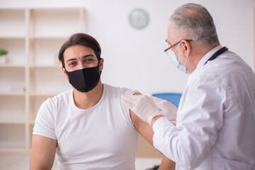 Young male patient visiting old doctor in vaccination concept