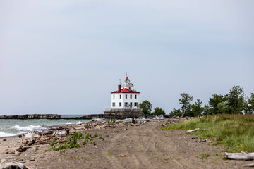 Fototapeta na wymiar Fairport Harbor West Breakwater Lighthouse on Lake Erie coastline with driftwood