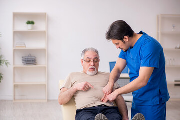 Obraz premium Old male patient visting young male doctor