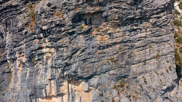 Rough surface and texture of rock on a vertical cliff. Geological layers of earth's crust. Sedimentary strata mountain formation on a rugged canyon wall.