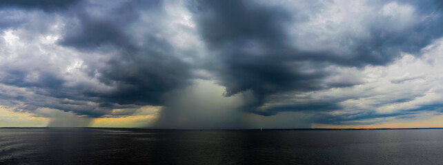 Dramatic dark seascape, panoramic view. Storm clouds and rain over the sea, cloudy weather, shower, storm