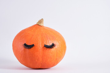 pumpkin with false eyelashes on gray background