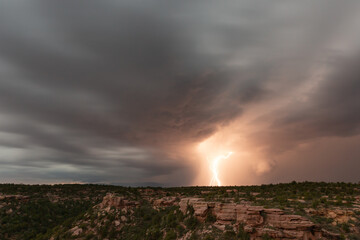 A bolt of lightning drops down from dark rolling clouds to the mountains behind Smith's Mesa in Southern Utah. 