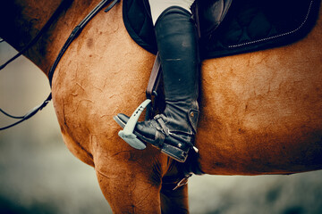Equestrian sport. The leg of the rider in the stirrup, riding on a horse.