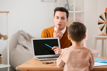 Speech therapist working with little boy in office