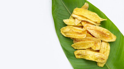 Banana slice chips on green leaves on white background.