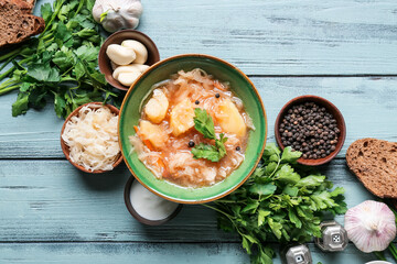 Composition with tasty sauerkraut soup on color wooden background