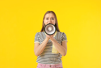 Obraz premium Young woman shouting into megaphone on color background