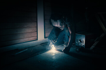 A worker welding a piece of iron in the dark