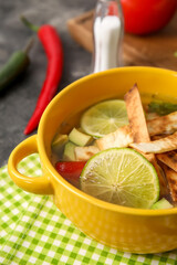 Bowl of tasty Sopa de Lima soup on table, closeup