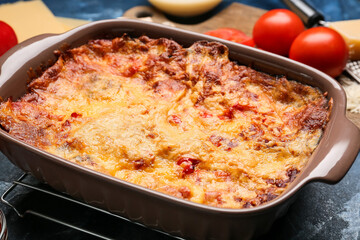 Baking dish with tasty vegetable lasagna on color background