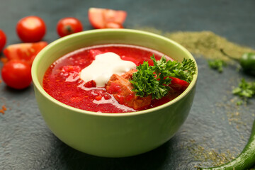 Bowl of tasty borscht with sour cream on dark background