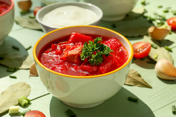 Bowl with tasty borscht on color wooden background