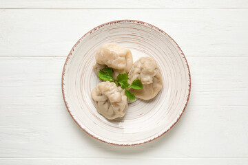 Plate with tasty dumplings on light wooden background